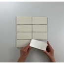 Zeven witte rechthoekige blokken in een raster met handen die een Atlas Ivory Mate vasthouden