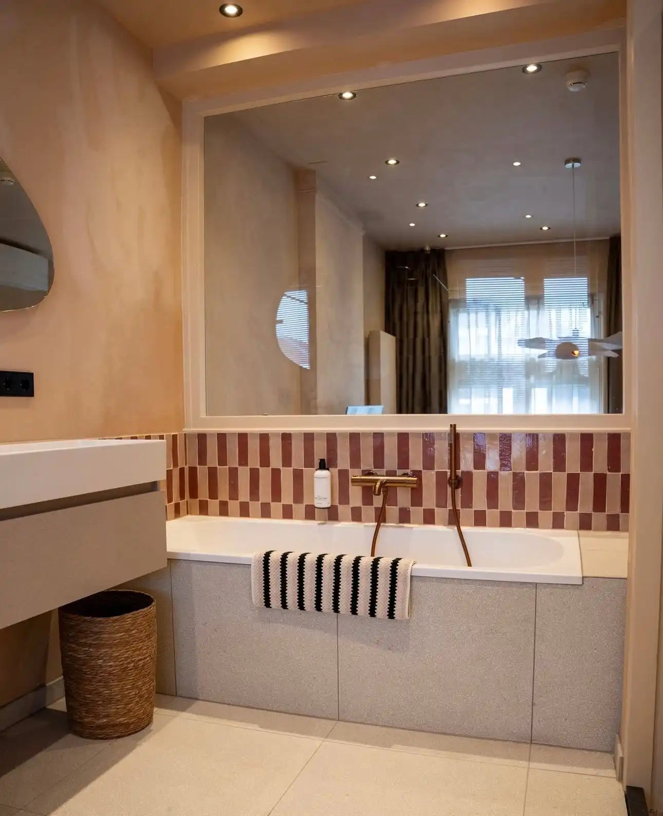 Witte en gouden badkuip met mozaïek tegelaccenten.