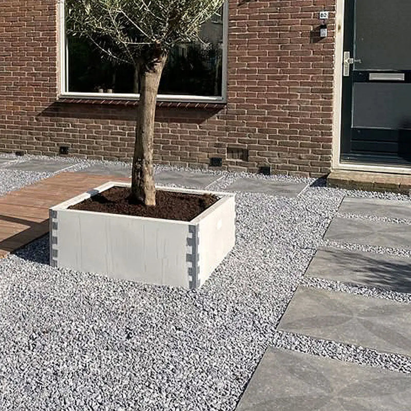 Witte plantenbak met zwaluwstaarten en boom, perfect voor keramische tuintegels.