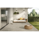 Rattan buitenbed met gele kussens en geweven poef op Duolith Fossil 60x60 vloer