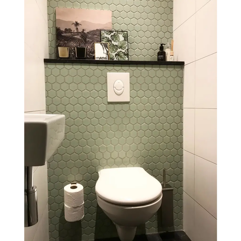 Witte porseleinen toilet met gesloten deksel tegen lichtgroene hexagonale wand van Light Green Edge Glossy