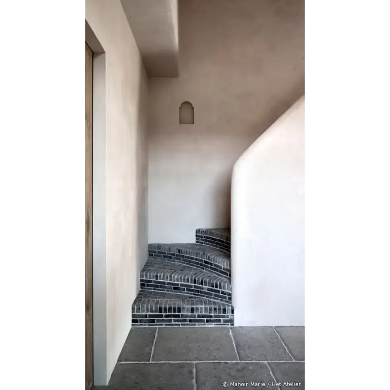 Curved stone staircase with black iron railings in Ambachtelijke Firenze Greige