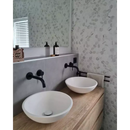 Twee witte vessel-wastafels op een houten badkamermeubel met zwarte kranen voor Carrara Wit Mat