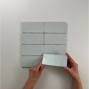 Witte rechthoekige tegels van Atlas Aqua Mate in een grid met handen die er eentje vasthouden