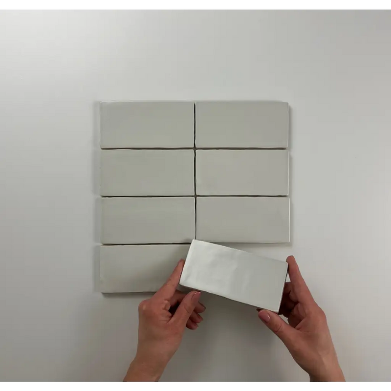 Witte rechthoekige blokken in een grid met handen die een Atlas Pearl Mate block vasthouden