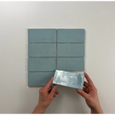 Rechthoekige blauw-grijze Atlas Sky Brillo tegels in een grid met een tegel in de hand