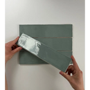 Handen die de beschermfolie van een groene keramische tegel Colonial Jade glans verwijderen