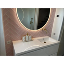 Ronde verlichte spiegel met LED boven een witte wastafel en Colonial Pink mat