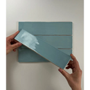 Glanzend blauw-groen keramisch tegel van Colonial Sky Glans 7,5x30 in handen