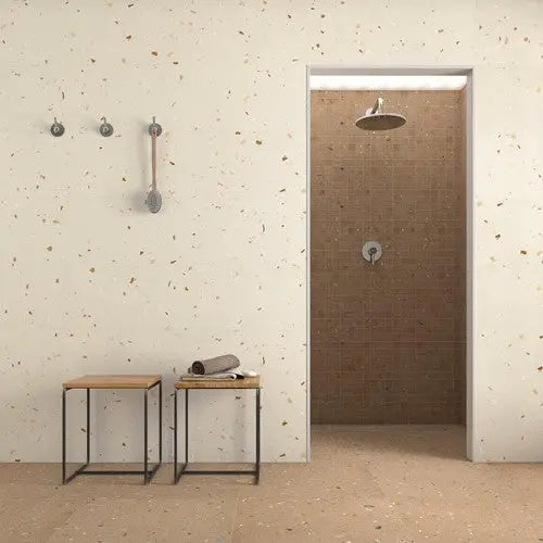 Deur met een douchekop zichtbaar, omgeven door grote 80x80 terrazzo tegels