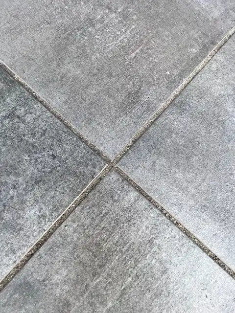 Grijze betonnen tegelvloer met voeglijnen.