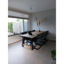 Houten eettafel met zwarte stoelen en pampasgras op Habitat Taupe mat 75x75