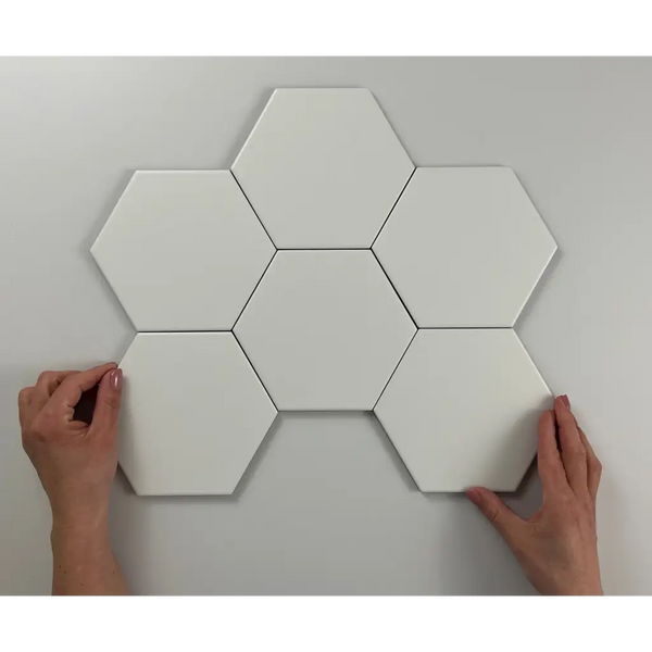 Zeven witte hexagonale tegels in bloemenpatroon op de Hexagon Timeless White mat 15x17