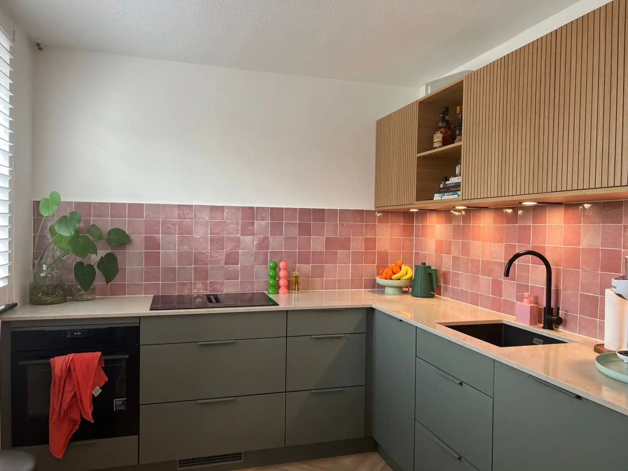 Moderne keuken met roze tegelachterwand.