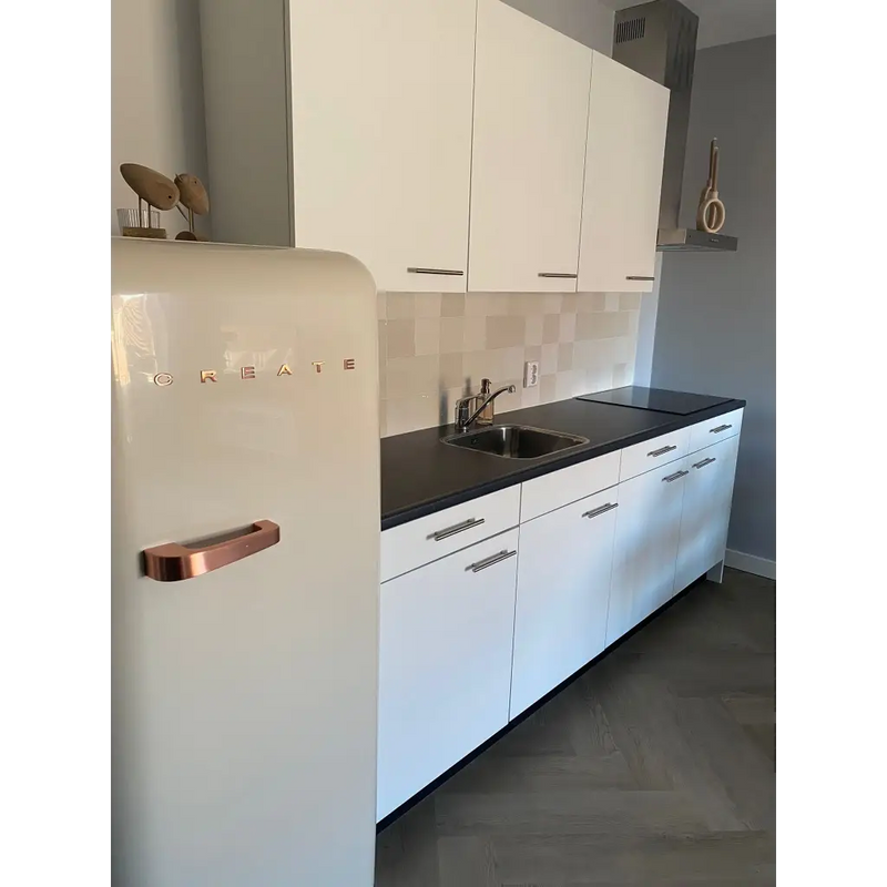 Moderne witte keuken met zwarte countertops en koperaccenten, Moos Ivory Glans Handvorm 13x13