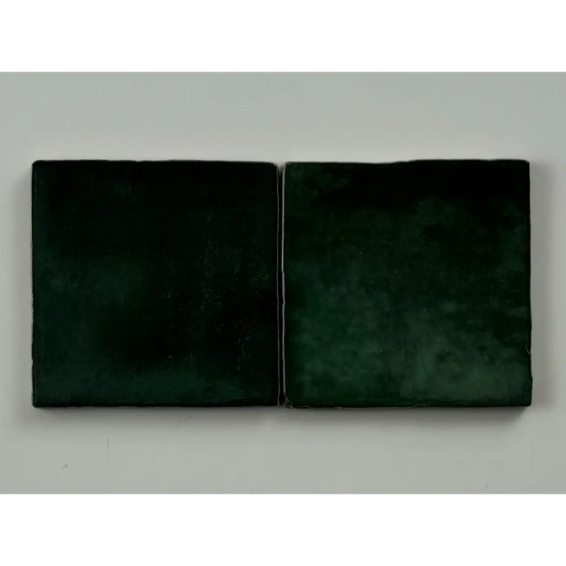 Twee donker groen glans 10x10 keramische tegels met matte afwerking en subtiele textuur
