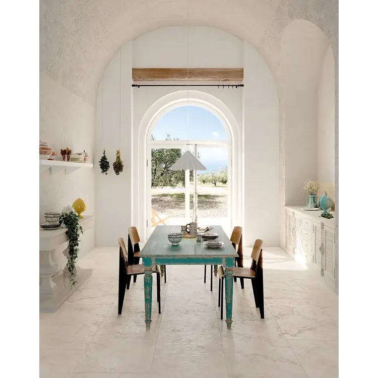 Turquoise dining table with wooden chairs under an arched window in Vento Del Sud Bianco 30x60 rett