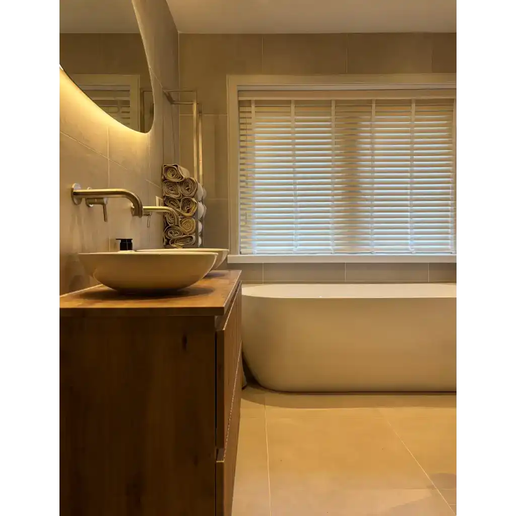 Witte vrijstaande badkuip met modern design en houten kast.