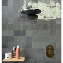 Ronde zwarte regendouchekop op een tegelwand met Zelliges Alhambra 40 Gris Fonce 10x10